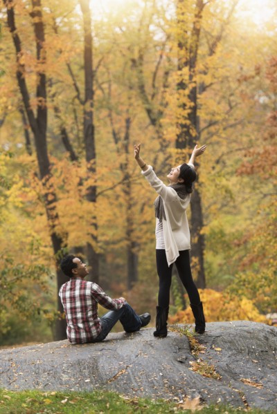 Woman cheering with arms outstretched near boyfriend in park
