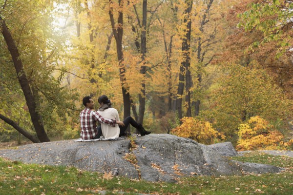 Asian couple hugging on rock in park