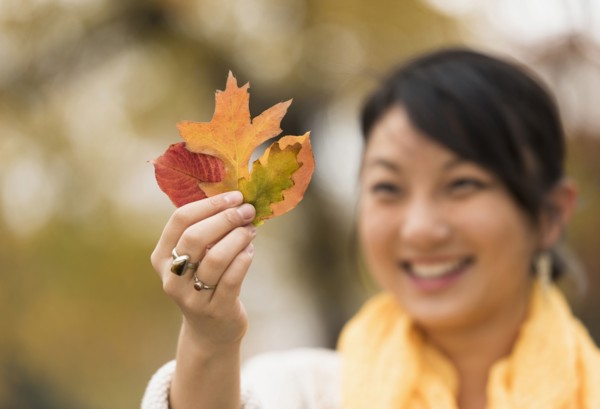 Asian woman admiring autumn leaves outdoors