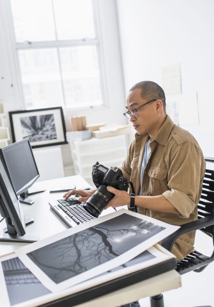 Korean photographer using computer at desk
