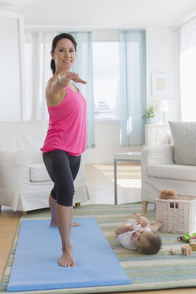 Mixed race mother practicing yoga and watching baby at home