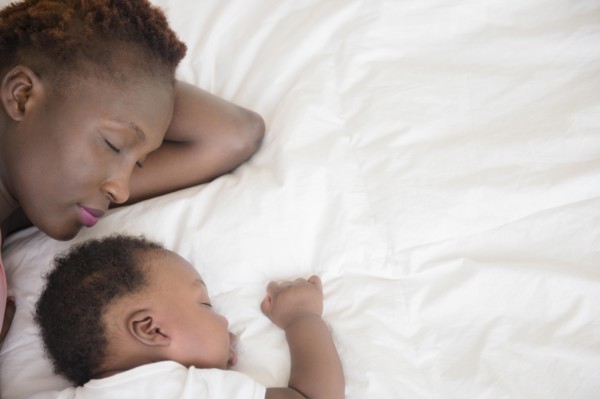 Black mother and son sleeping on bed