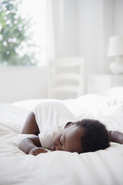Black baby sleeping on bed