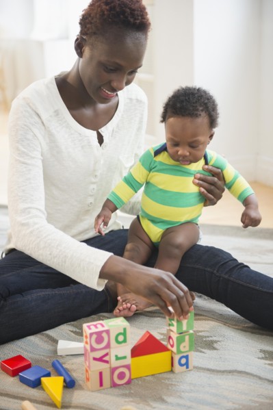 Black mother playing with baby boy in living room