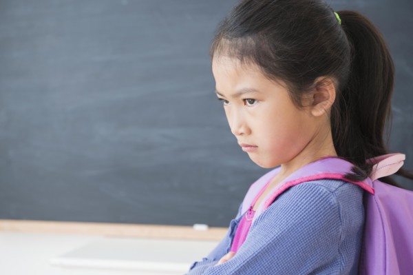 Frowning Vietnamese girl standing in classroom