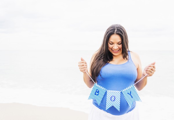 Pregnant mixed race woman holding boy banner on beach