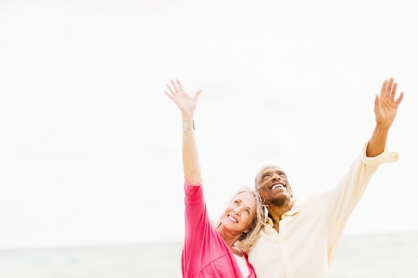 Older couple cheering and hugging on beach