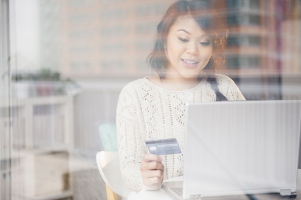 Pacific Islander woman shopping online on laptop behind window