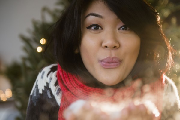 Pacific Islander woman blowing snow at Christmas