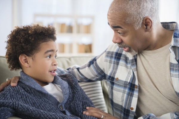 Mixed race grandfather and grandson talking on sofa