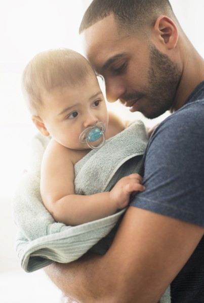 Father drying baby son with towel after bath