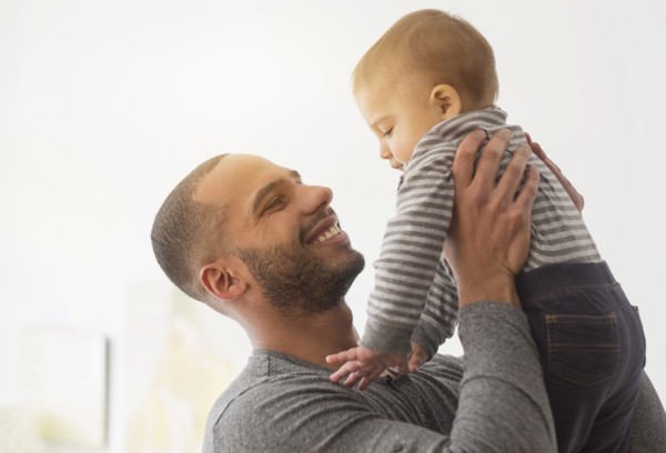 Smiling father playing with baby son
