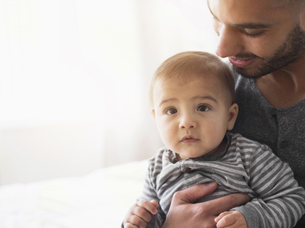 Smiling father holding baby son on bed