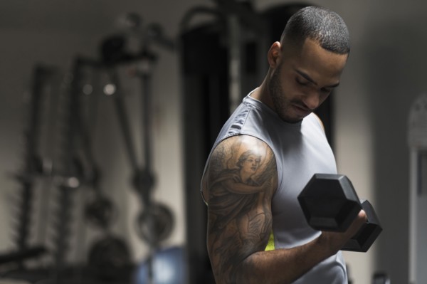 Close up of Hispanic man lifting weights in gym