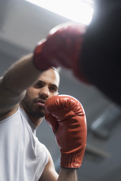 Close up of Hispanic man punching bag in gym