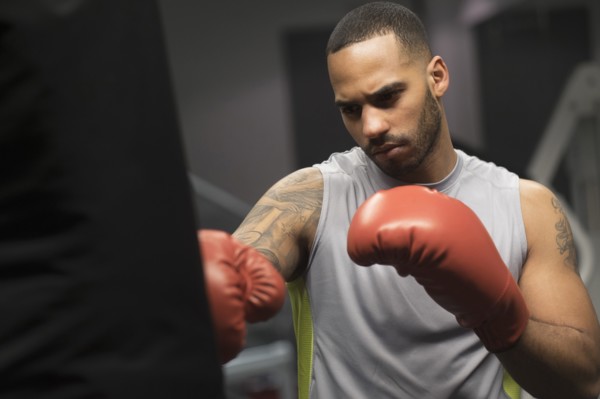 Close up of Hispanic man punching bag in gym