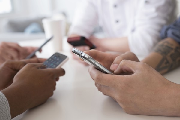 Close up of friends texting with cell phones at table