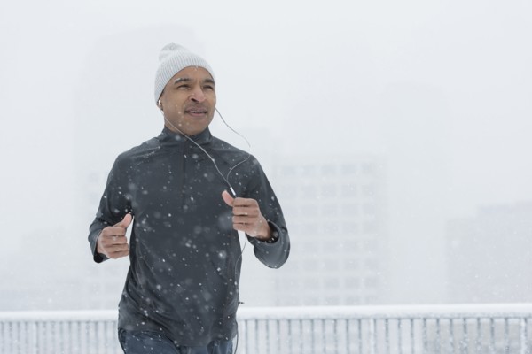 Black runner jogging in snow