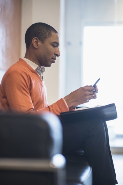 Black businessman using cell phone in office lobby