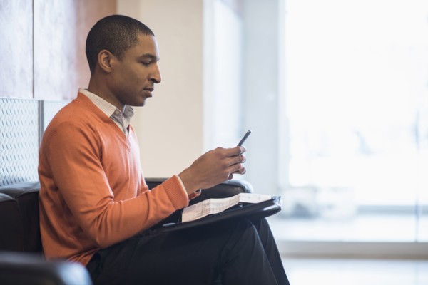 Black businessman using cell phone in office lobby