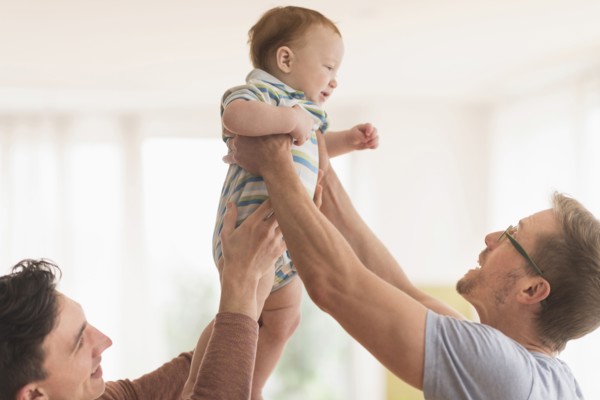Caucasian gay fathers holding baby