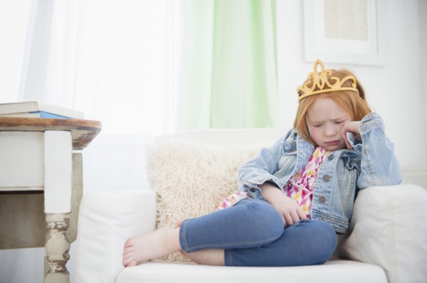 Upset Caucasian girl pouting in armchair