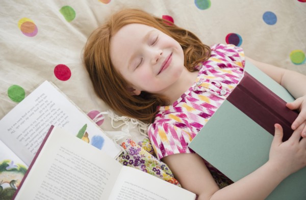 Caucasian girl reading books on bed