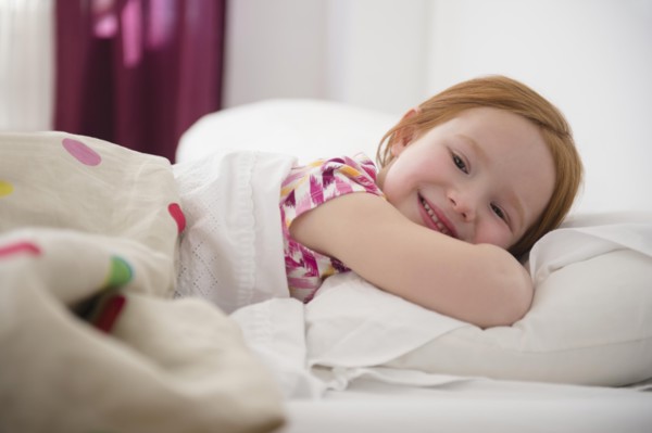 Smiling Caucasian girl laying in bed
