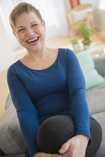 Laughing Caucasian woman sitting on sofa
