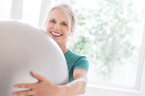 Older Caucasian woman holding exercise ball in gym