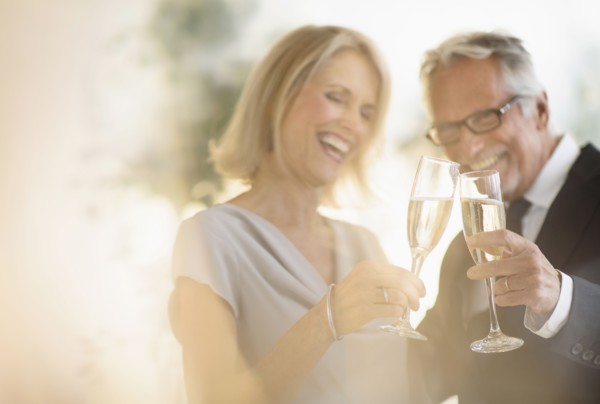 Smiling older Caucasian couple toasting with champagne