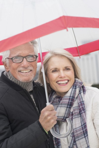Older Caucasian couple standing under umbrella