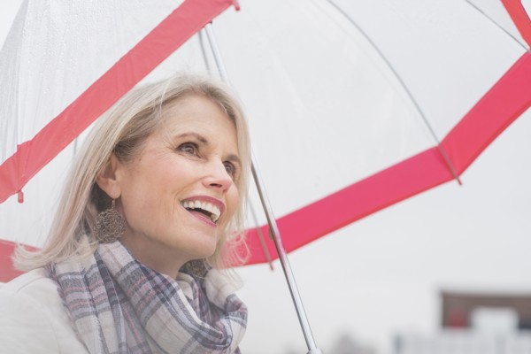 Older Caucasian woman standing under umbrella