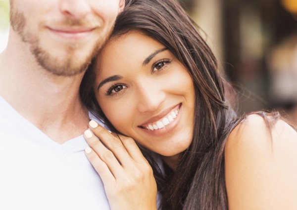 Hispanic woman hugging boyfriend on sidewalk