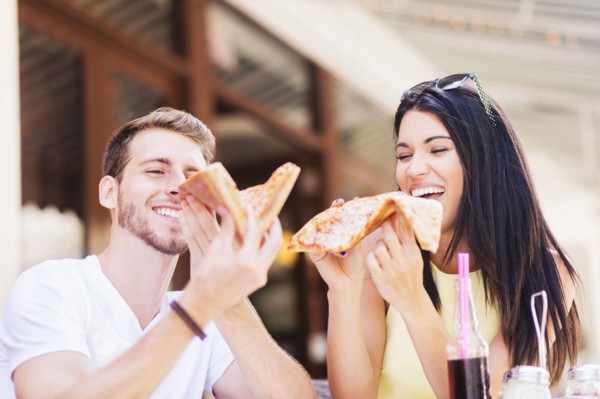 Hispanic couple eating pizza at cafe