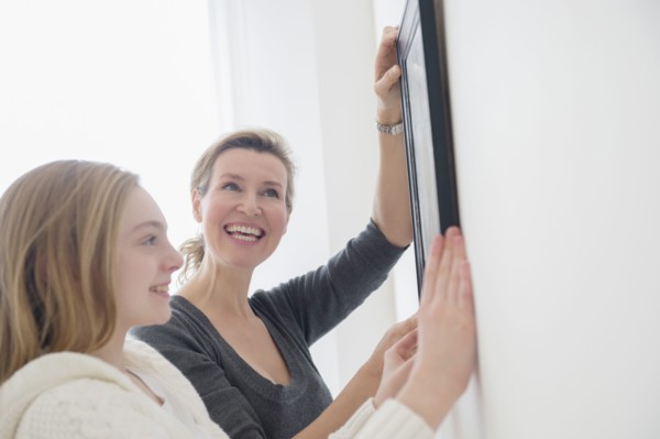 Caucasian mother and daughter hanging picture on wall