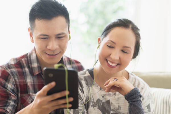 Laughing couple watching digital tablet on sofa