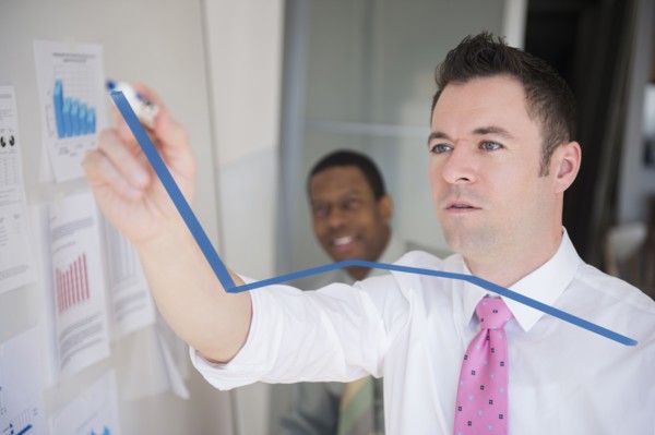 Businessman writing graph on glass wall in office