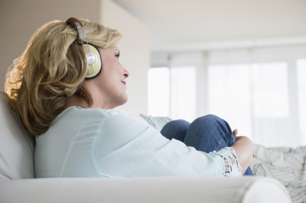 Caucasian woman listening to headphones on sofa
