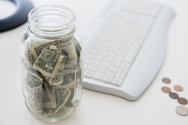 Close up of savings jar near computer keyboard