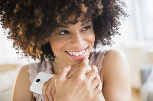 Smiling mixed race woman holding cell phone