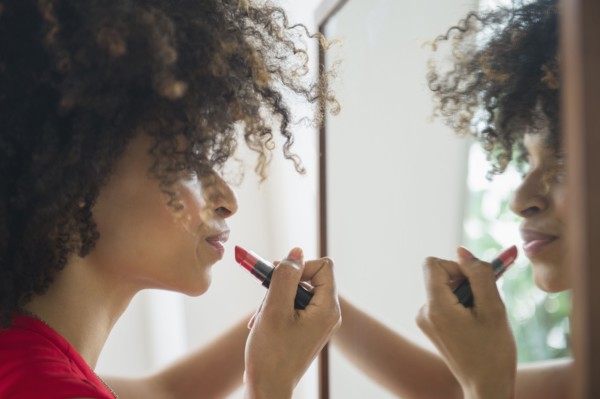 Mixed race woman applying lipstick in mirror