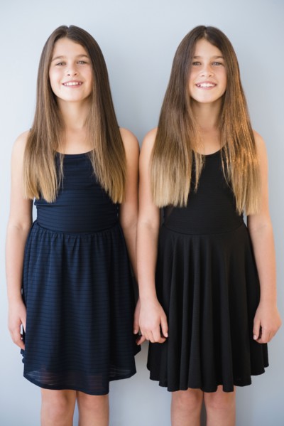Caucasian twin sisters wearing dresses