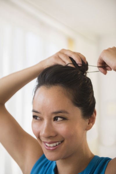 Chinese woman tying her hair in bun