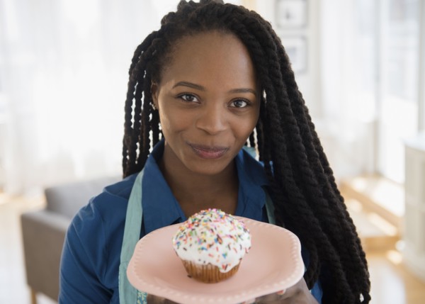 Black woman holding cupcake on plate