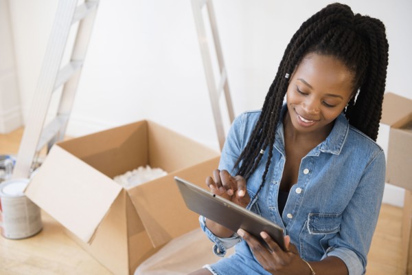 Black woman using digital tablet in new home