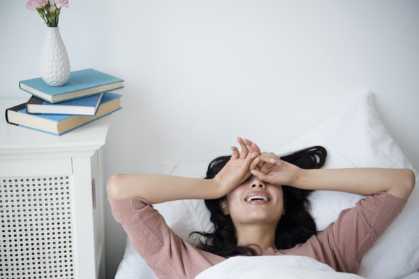 Hispanic woman waking up in bed