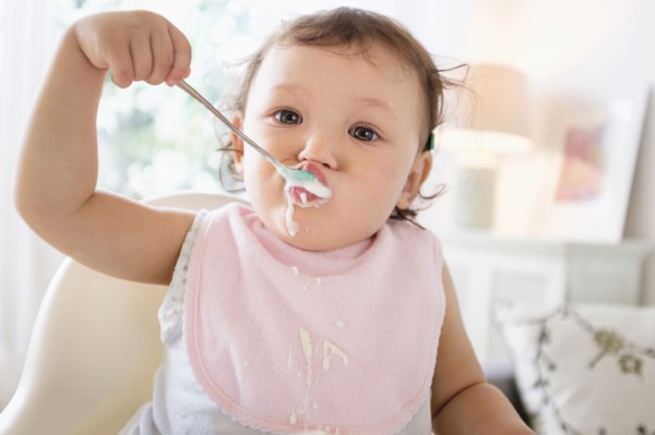 Mixed race baby girl eating yogurt