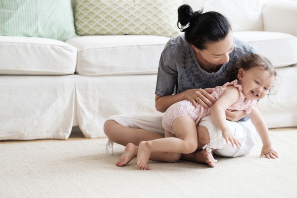 Mother and baby daughter playing in living room