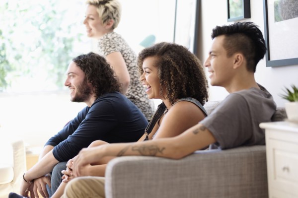 Friends watching television on sofa